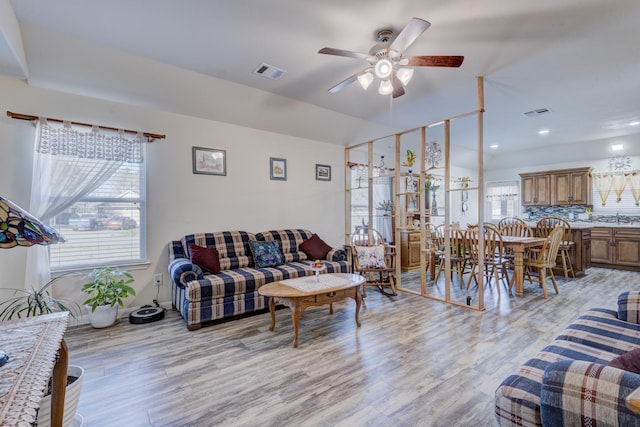 living room featuring lofted ceiling, sink, light hardwood / wood-style floors, and ceiling fan