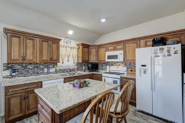 kitchen featuring lofted ceiling, sink, white appliances, backsplash, and a kitchen island