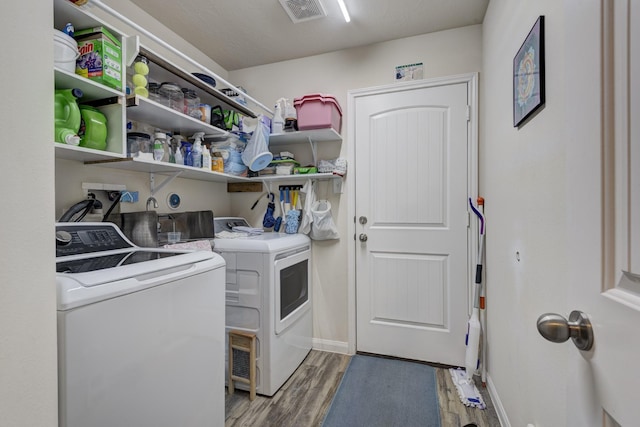 laundry room with separate washer and dryer and hardwood / wood-style flooring