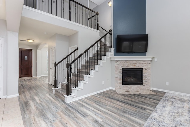 unfurnished living room with a fireplace, a towering ceiling, and wood-type flooring