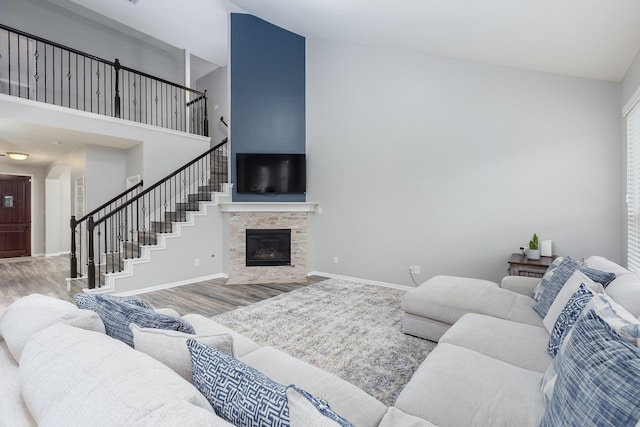 living room featuring wood-type flooring, high vaulted ceiling, and a tile fireplace