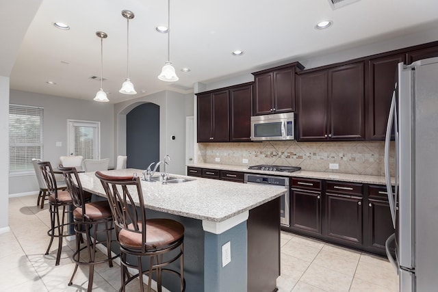 kitchen featuring pendant lighting, sink, a breakfast bar area, stainless steel appliances, and a center island with sink