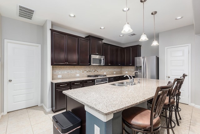 kitchen with a kitchen island with sink, sink, stainless steel appliances, and dark brown cabinetry