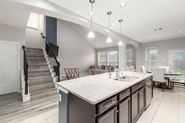 kitchen with an island with sink, sink, dark brown cabinetry, and decorative light fixtures