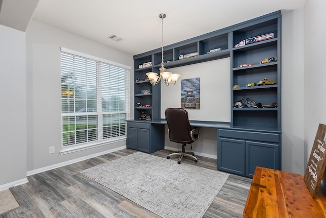 office with dark hardwood / wood-style floors, an inviting chandelier, and built in shelves