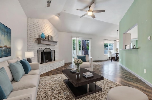 living room featuring lofted ceiling, a fireplace, dark hardwood / wood-style flooring, and ceiling fan