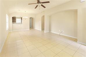 spare room with tile patterned flooring and ceiling fan with notable chandelier