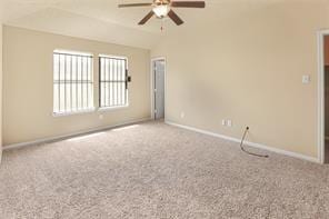 carpeted spare room featuring vaulted ceiling and ceiling fan