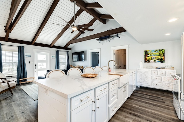 kitchen featuring lofted ceiling with beams, sink, light stone counters, and white cabinets