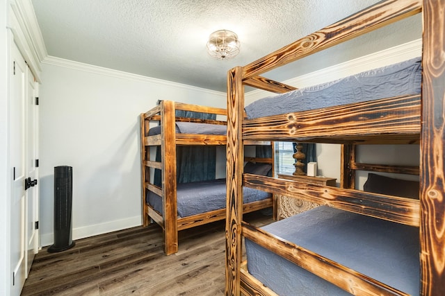 bedroom with crown molding, dark hardwood / wood-style floors, and a textured ceiling