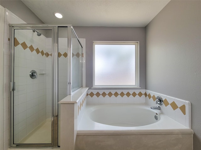 bathroom featuring independent shower and bath and a textured ceiling