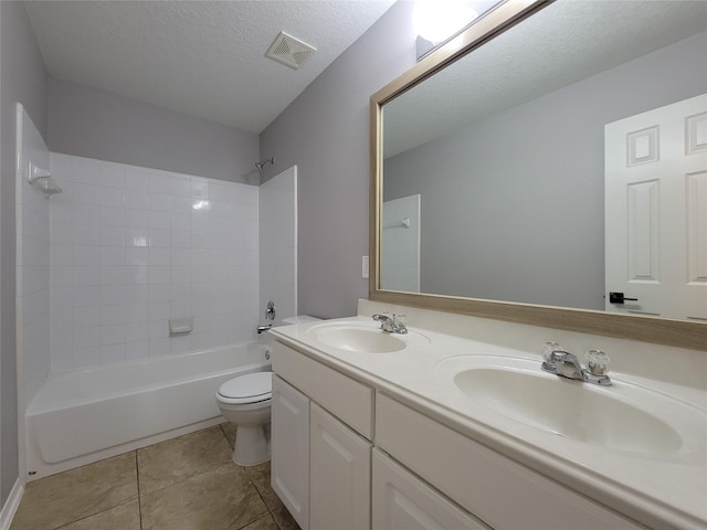 full bathroom featuring tiled shower / bath, vanity, toilet, tile patterned floors, and a textured ceiling