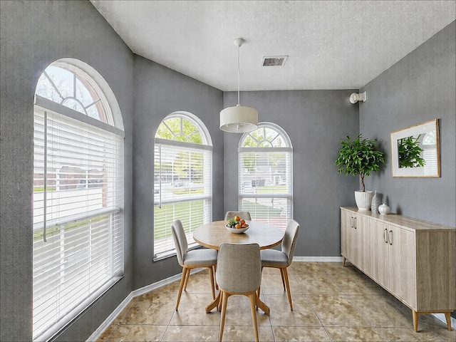 dining space with a textured ceiling and light tile patterned floors