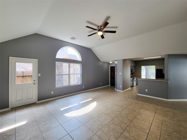 unfurnished living room with lofted ceiling, light tile patterned floors, a textured ceiling, and ceiling fan