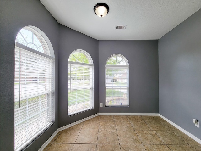 unfurnished room with a textured ceiling and light tile patterned floors