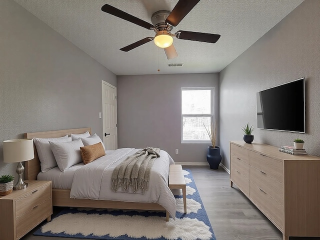 bedroom featuring ceiling fan, a textured ceiling, and light wood-type flooring