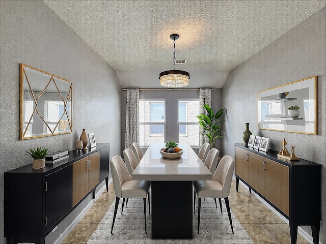 dining space with vaulted ceiling, light tile patterned flooring, and a textured ceiling