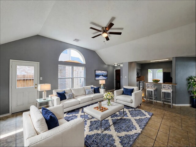 living room featuring lofted ceiling, light tile patterned floors, and ceiling fan