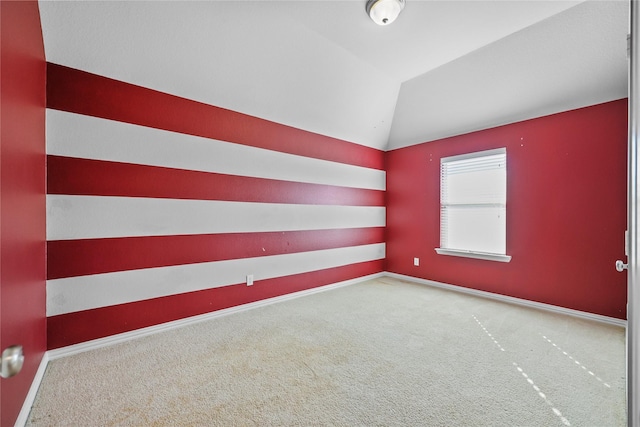 carpeted empty room featuring lofted ceiling