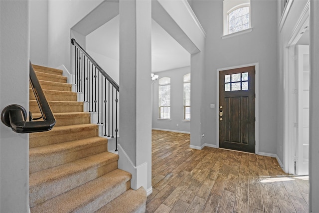 entryway with a healthy amount of sunlight, a chandelier, hardwood / wood-style floors, and a high ceiling