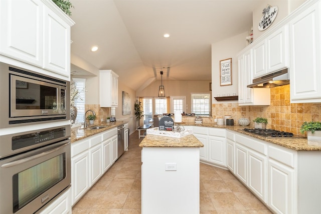 kitchen with appliances with stainless steel finishes, white cabinetry, sink, a center island, and kitchen peninsula