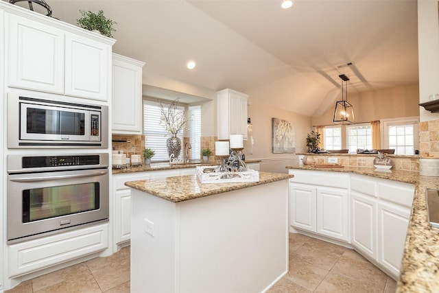 kitchen with white cabinetry, a center island, appliances with stainless steel finishes, kitchen peninsula, and pendant lighting