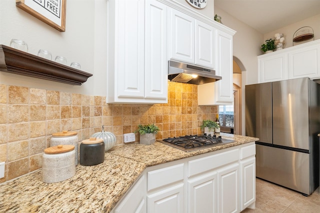 kitchen with stainless steel appliances, light tile patterned floors, decorative backsplash, and white cabinets