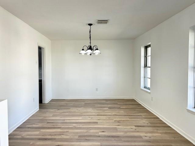 unfurnished dining area featuring light hardwood / wood-style flooring and a notable chandelier