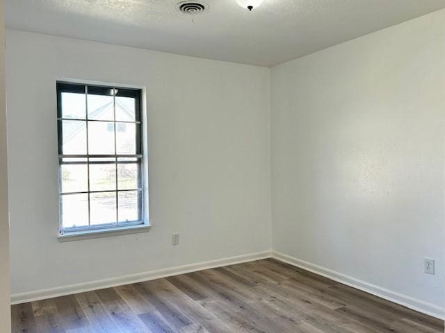 spare room featuring hardwood / wood-style floors and a textured ceiling