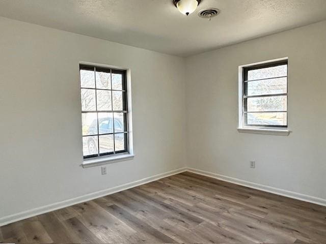 spare room with hardwood / wood-style floors, a wealth of natural light, and a textured ceiling