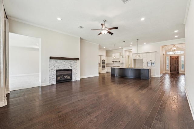 unfurnished living room featuring crown molding, a fireplace, dark hardwood / wood-style floors, and ceiling fan