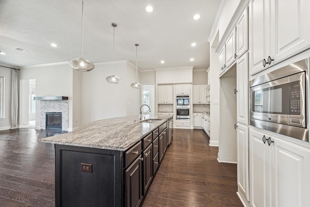 kitchen featuring white cabinetry, an island with sink, sink, hanging light fixtures, and stainless steel appliances