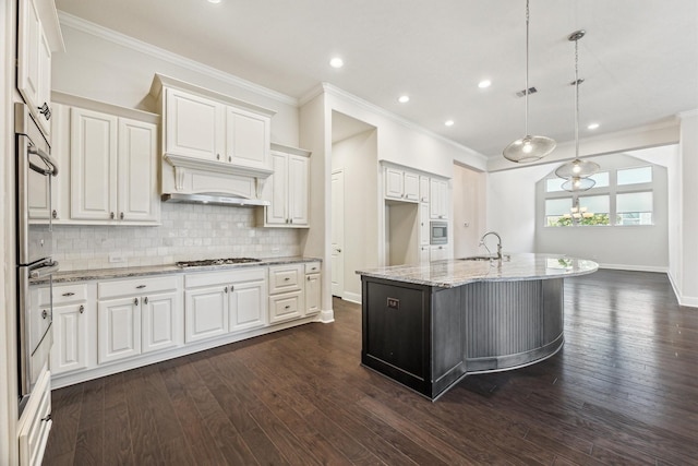 kitchen with sink, white cabinetry, hanging light fixtures, an island with sink, and light stone countertops