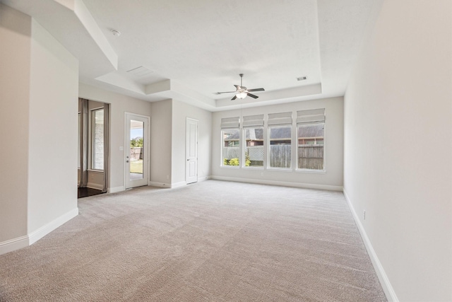 unfurnished living room with ceiling fan, a raised ceiling, and light carpet