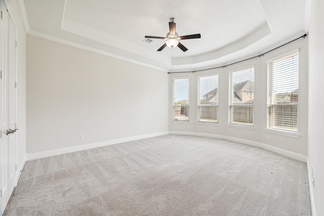 unfurnished room with a raised ceiling, ornamental molding, light colored carpet, and ceiling fan