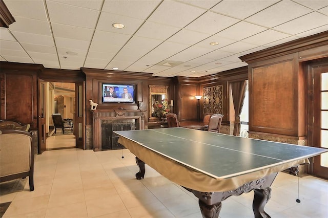 game room with a fireplace, ornamental molding, and a paneled ceiling