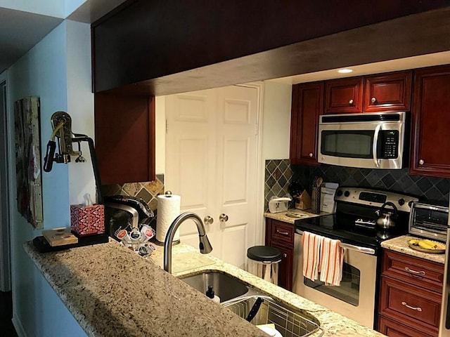 kitchen featuring light stone countertops, decorative backsplash, stainless steel appliances, and sink