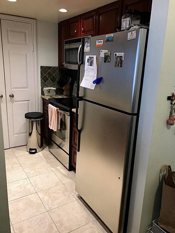 kitchen featuring appliances with stainless steel finishes, light tile patterned floors, and decorative backsplash