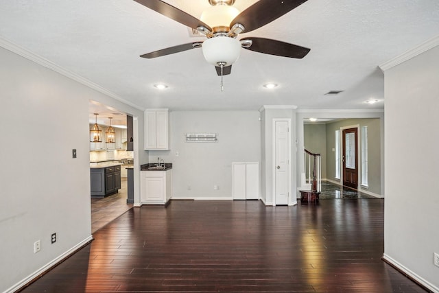 unfurnished living room featuring dark wood-type flooring, ceiling fan, and crown molding