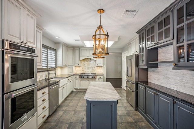 kitchen featuring sink, stainless steel appliances, a kitchen island, decorative backsplash, and a chandelier