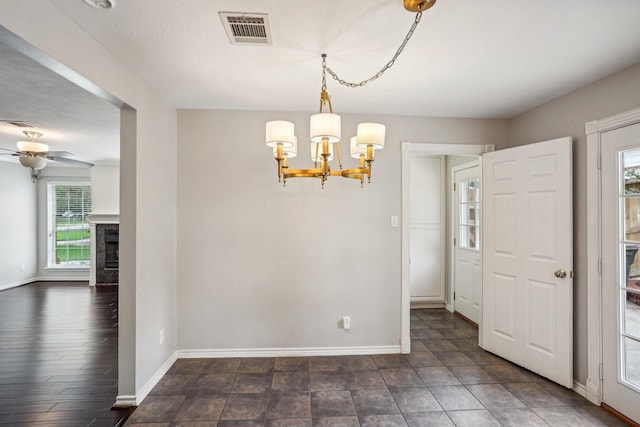 unfurnished dining area with a premium fireplace and ceiling fan with notable chandelier