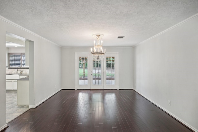 unfurnished room with hardwood / wood-style flooring, ornamental molding, a notable chandelier, and a textured ceiling