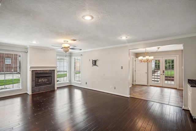 unfurnished living room with dark wood-type flooring, a textured ceiling, ornamental molding, a fireplace, and ceiling fan with notable chandelier