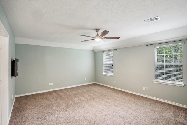 carpeted empty room featuring ceiling fan and a textured ceiling