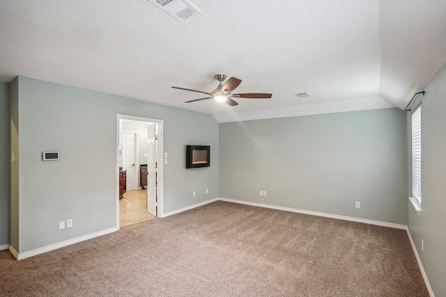 interior space with ceiling fan, lofted ceiling, ensuite bathroom, and light carpet