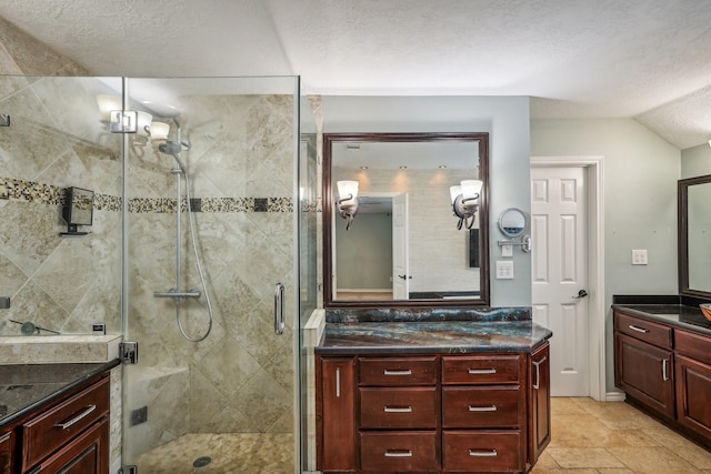 bathroom with vanity, lofted ceiling, a textured ceiling, and a shower with shower door