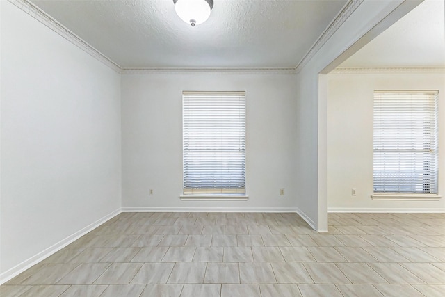 spare room featuring ornamental molding, a healthy amount of sunlight, and a textured ceiling