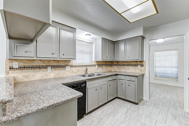 kitchen featuring gray cabinets, black dishwasher, sink, and backsplash