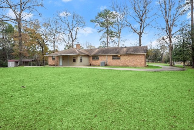 back of property with central AC and a lawn