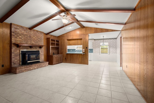 unfurnished living room featuring ceiling fan, vaulted ceiling with beams, light tile patterned floors, and wooden walls